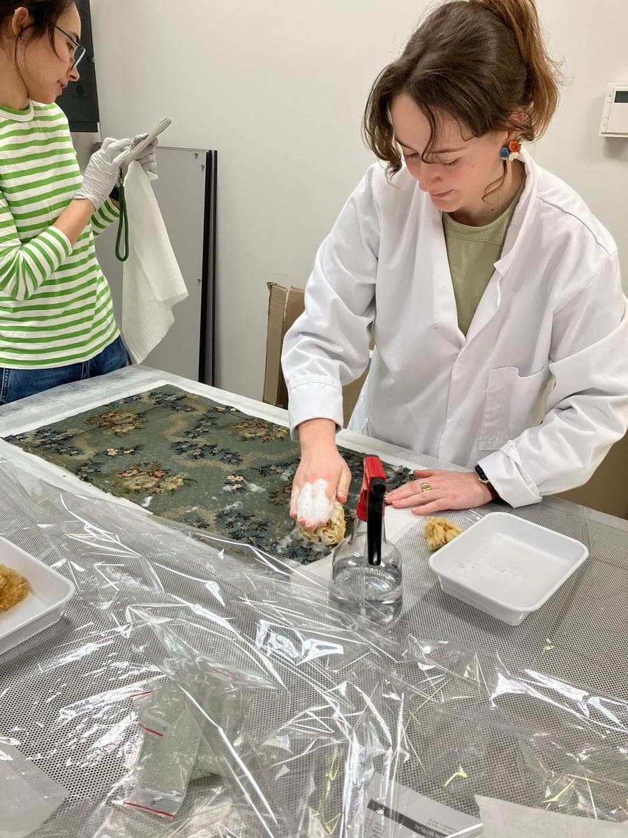 Textile conservator cleaning fabric with a sponge